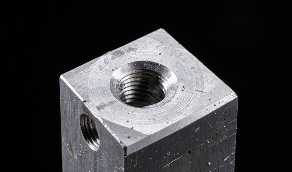 Sectioned steel block showing a deep blind hole and an internal thread