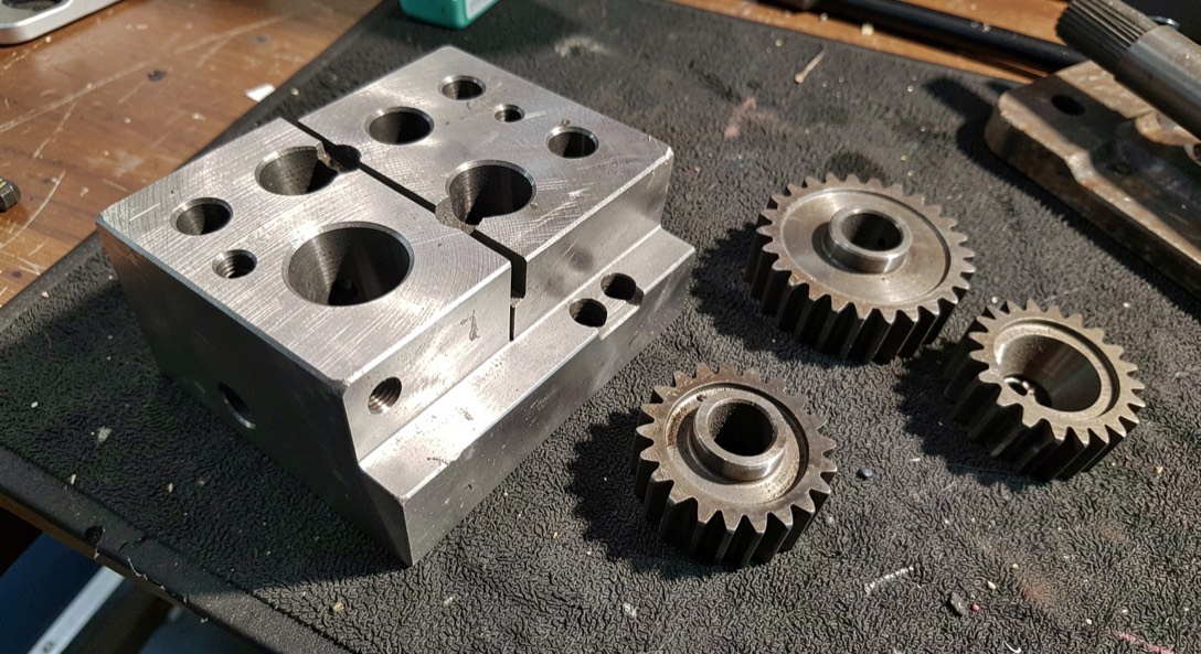 Cutaway of a hydraulic manifold and a gear set laid out on a workshop table